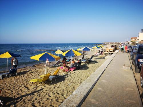 a beach with people sitting under umbrellas and the ocean at Anthoula Sunrise in Kokkíni Khánion