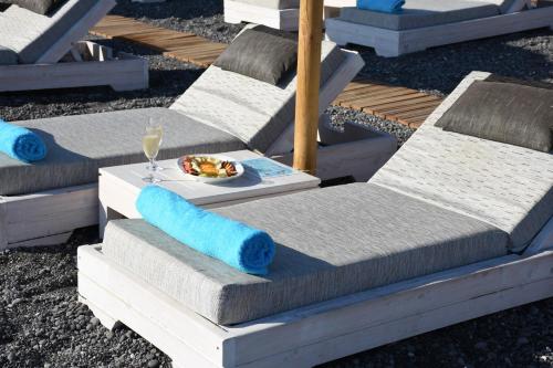 a group of chairs with a plate of food and a glass of wine at Arion Bay Hotel Santorini in Kamari