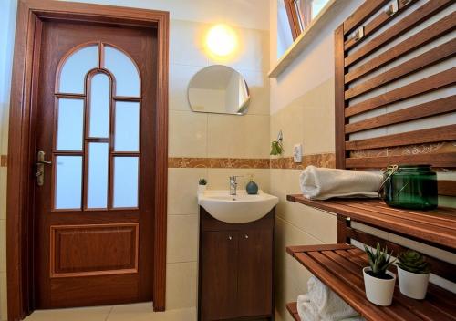 ein Badezimmer mit einem Waschbecken und einer Holztür in der Unterkunft Apartament plażowy Ukiel in Olsztyn