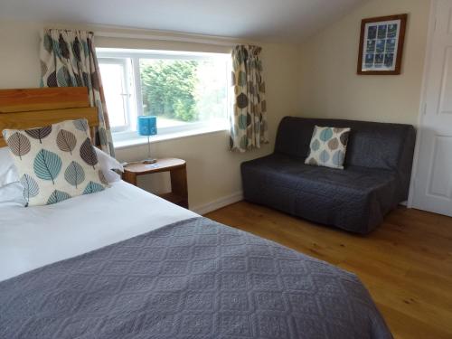 um quarto com uma cama, uma cadeira e uma janela em Manor Farm Stay em Sutton-on-Sea