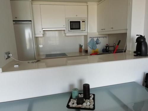 cocina con armarios blancos y encimera en Appartement Port Gran Oceanic 2, en Roses