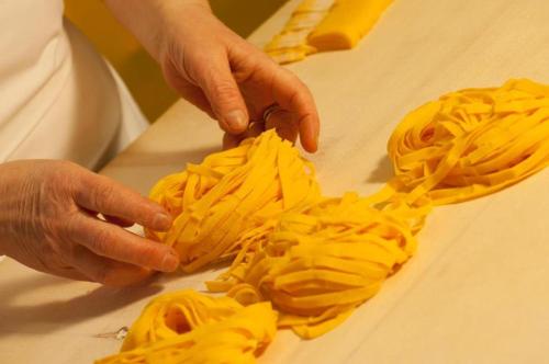 a person cutting up some pasta on a cutting board at Residenza i Platani in Santarcangelo di Romagna