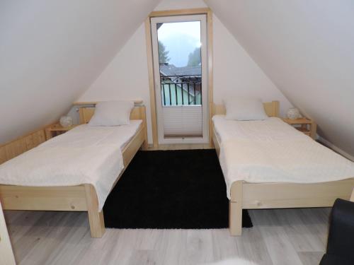 two beds in a room with a window at Na Świerkowym Strychu in Szczawnica