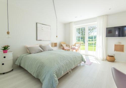 a white bedroom with a bed and a table and chairs at Kunstart20 in Saltum