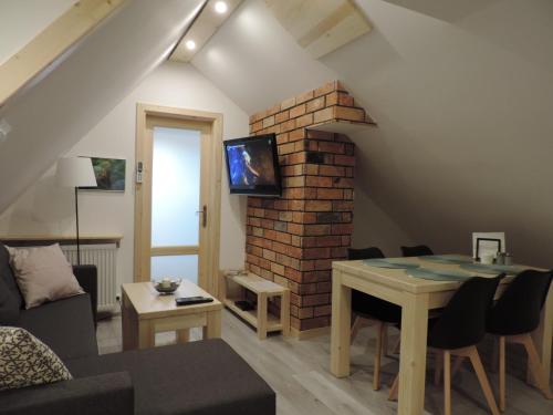 a living room with a table and a brick wall at Na Świerkowym Strychu in Szczawnica