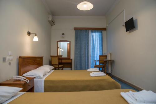 a hotel room with two beds and a mirror at Hotel Liberty in Mesolongion