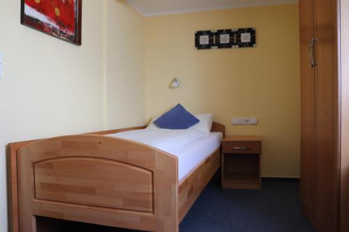 a small bedroom with a wooden bed with a blue pillow at Hotel Zum Waldstein in Weißenstadt