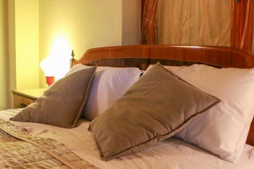 a bed with white pillows and a wooden head board at Spighe Paglia e Girasole in Candia Canavese
