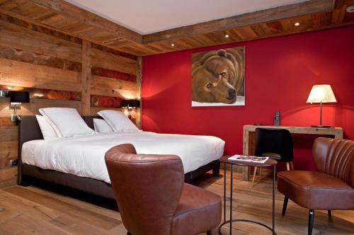 a hotel room with a bed, chair, table and lamp at Chalet-Hôtel La Marmotte, La Tapiaz & SPA, The Originals Relais (Hotel-Chalet de Tradition) in Les Gets