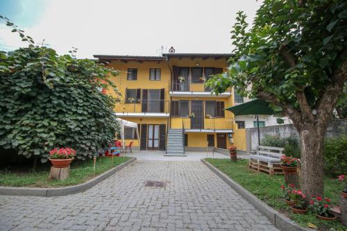 a yellow apartment building with a tree and a sidewalk at Spighe Paglia e Girasole in Candia Canavese