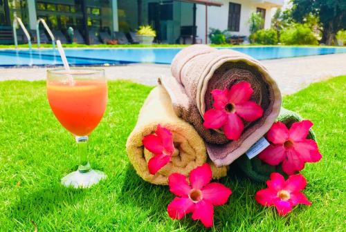 a glass of orange juice next to a towel and flowers at Saman Resort Yala in Tissamaharama