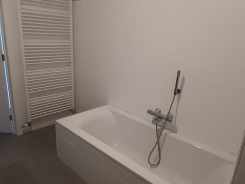 a white bathroom with a bathtub with a hose at Residentie Koen in Ostend