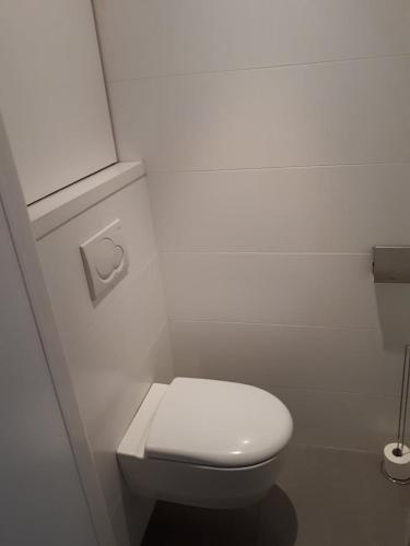 a white bathroom with a toilet with a white lid at Residentie Koen in Ostend
