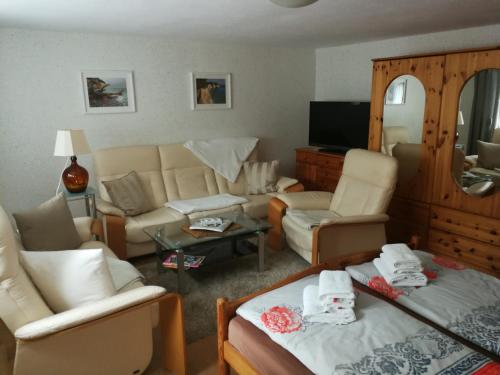 FerienWohnung Gebhardt في بينز: غرفة معيشة مع أريكة وكراسي وتلفزيون
