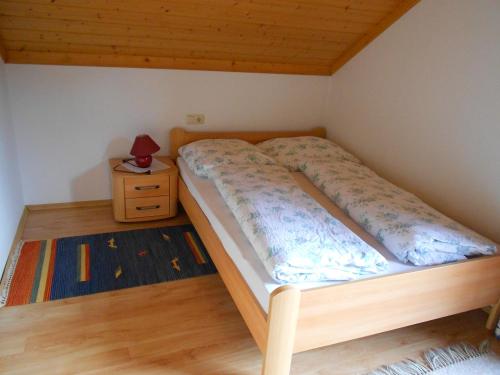 een bed in een kleine kamer met een nachtkastje bij Ferienwohnung Schmiedbauer in Gosau
