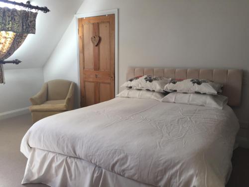 a bedroom with a large white bed and a chair at Greenhill Farm Barn B&B in Sutton under Brailes