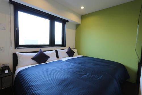 a bedroom with a bed with a blue blanket and a window at HOTEL LiVEMAX Ueno-Ekimae in Tokyo