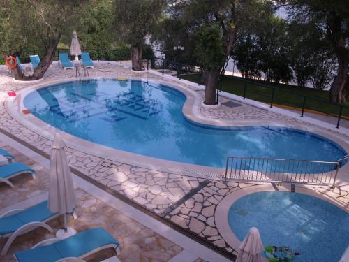 a large swimming pool with chairs and umbrellas at Saint Nicholas Beach Resort in Dassia