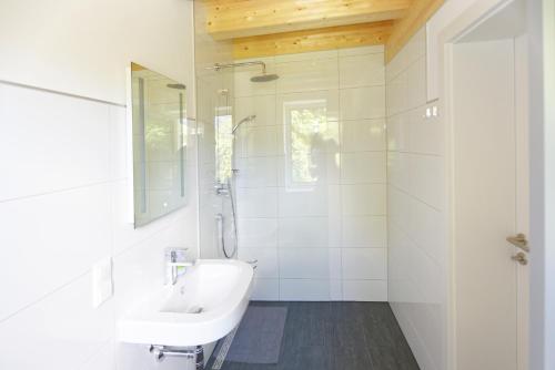 ein weißes Bad mit einem Waschbecken und einer Dusche in der Unterkunft Ferienwohnungen Unterleegut in Mühlbach am Hochkönig