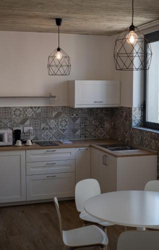a kitchen with white cabinets and a table and chairs at Chapter 5 Hotel in Taʼ Xbiex