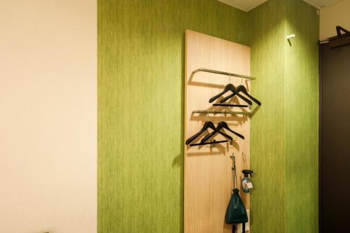 a room with a green wall with hangers on a door at Shin Osaka Esaka Tokyu REI Hotel in Suita