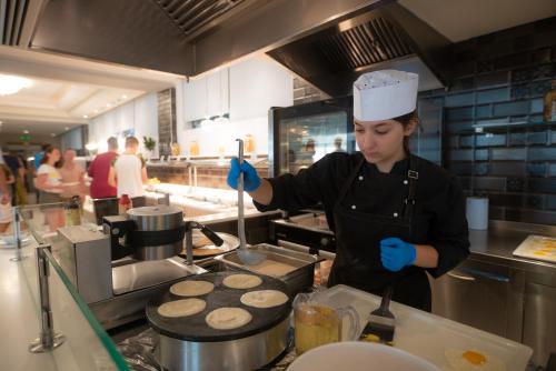 a woman in a kitchen preparing food in a kitchen at Elea Beach Hotel in Dassia