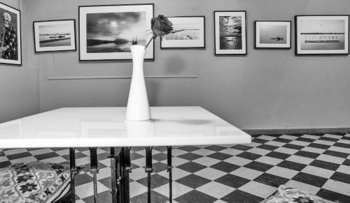 a white vase on a table in a room with pictures at Hotel Liberty in Mesolongion