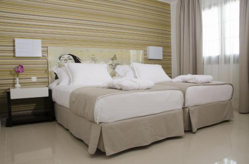 a bedroom with two beds with white pillows at Boutique Hotel H10 White Suites - Adults Only in Playa Blanca