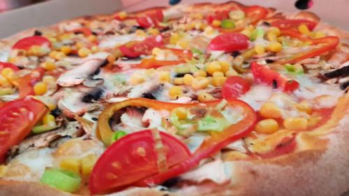 a pizza with peppers and vegetables on a plate at Camere de Inchiriat IGLOO in Predeal