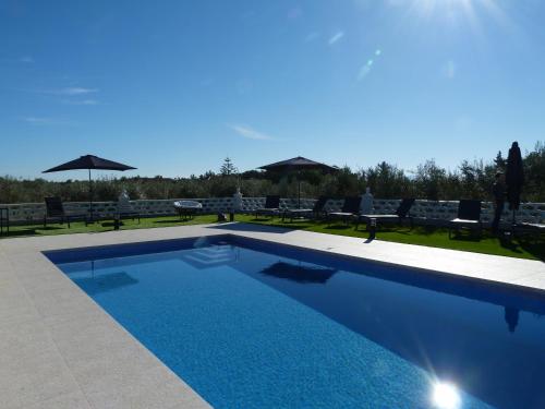 a swimming pool in a yard with chairs and umbrellas at Finca Tres Molinos B&B in Roldán