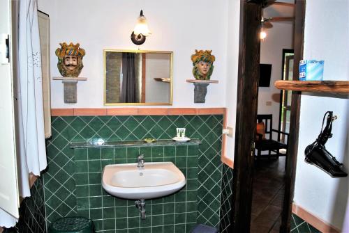 uma casa de banho com azulejos verdes, um lavatório e um espelho. em B&B Terre Di Sicilia em Giardini Naxos