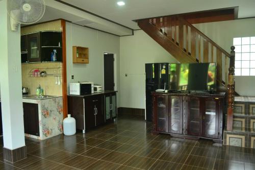 a room with a kitchen with a tv and a staircase at Bang Hon Homestay in Ko Yao Noi