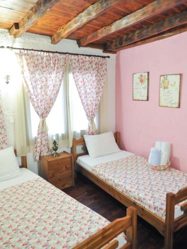 two beds in a room with pink walls and wooden ceilings at Guesthouse Xenios Zeus in Stavroupoli