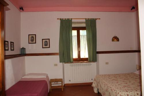 a bedroom with two beds and a window with green curtains at Il Casolare in Penna