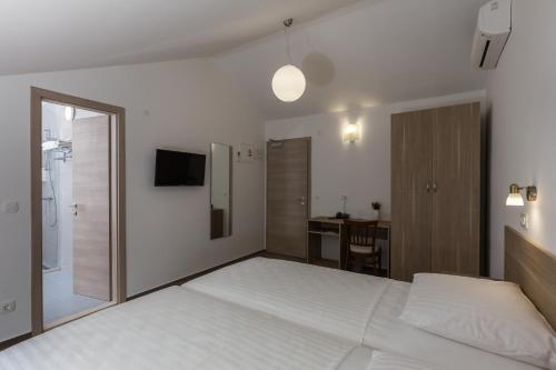 a bedroom with a large white bed and a desk at Hotel Vimbula - Komolac in Mokošica