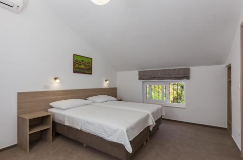 a white bedroom with a large bed and a window at Hotel Vimbula - Komolac in Mokošica