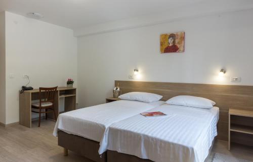 a bedroom with a bed and a desk and a table at Hotel Vimbula - Komolac in Mokošica
