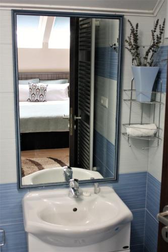 a bathroom with a sink and a mirror and a bed at Silva House in Deva