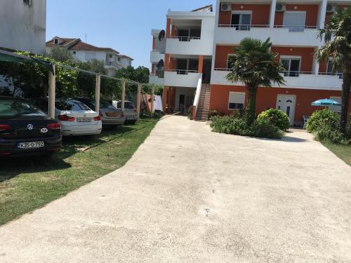 a parking lot with cars parked in front of a building at Robi Apartments in Ulcinj