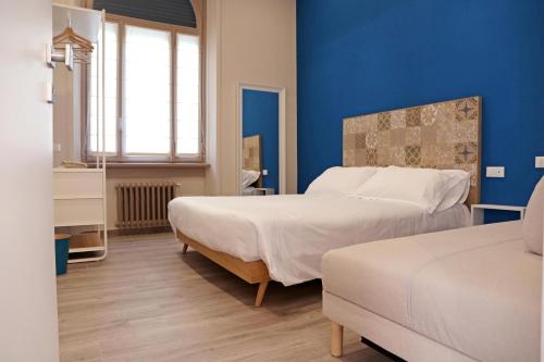 a bedroom with two beds and a blue wall at APP9 - rooms and apartments in Bergamo