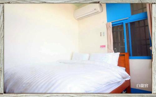 a bed with white sheets and pillows in a room at 福緣白龍宮海景 in Xiaoliuqiu