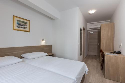 a bedroom with a white bed and a desk at Hotel Vimbula - Komolac in Mokošica