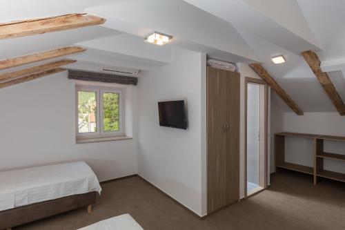 a bedroom with a bed and a tv on the wall at Hotel Vimbula - Komolac in Mokošica