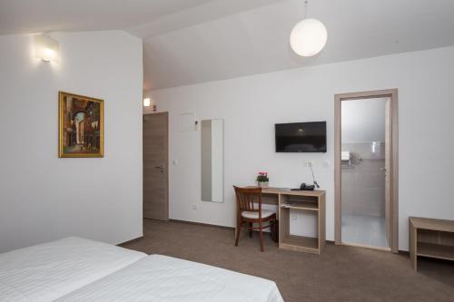 a hotel room with a bed and a desk and a table at Hotel Vimbula - Komolac in Mokošica