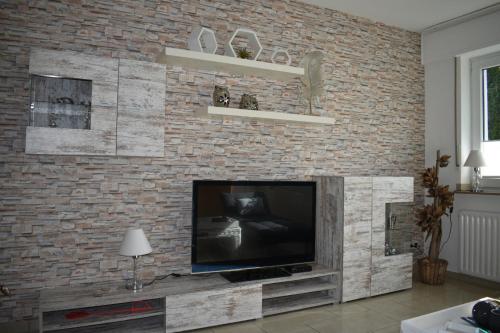 a living room with a television on a brick wall at My Home - Ferienwohnung in Lüdinghausen