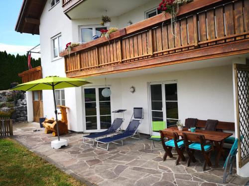 une terrasse avec une table, des chaises et un parasol dans l'établissement Jägerstüble, à Altusried