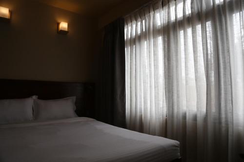 a bedroom with a bed and a window with curtains at Sabila Boutique Hotel in Kathmandu