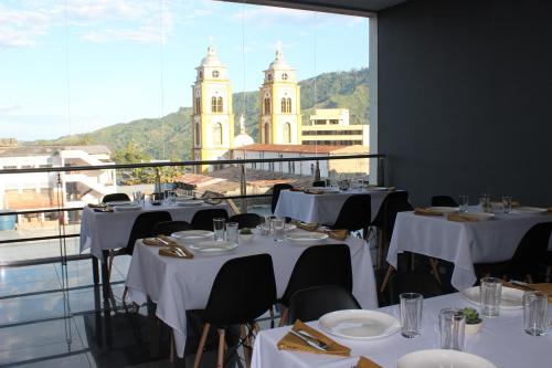 a restaurant with white tables and chairs and a large window at Hotel Doral Inn in Ibagué