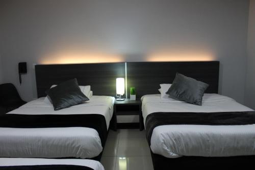 a hotel room with two beds and a table with a lamp at Hotel Doral Inn in Ibagué