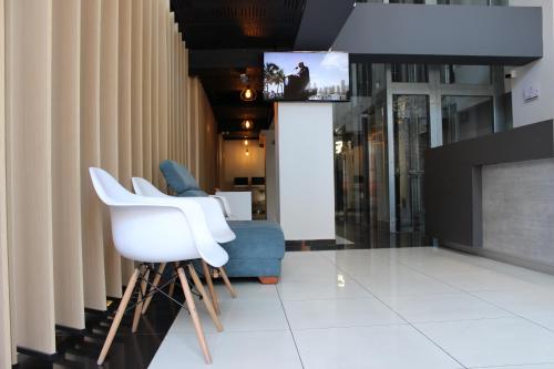 a living room with white chairs and a tv at Hotel Doral Inn in Ibagué